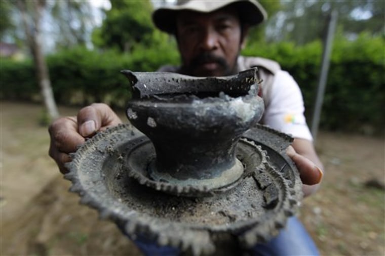 In this photo taken June 23, 2011, an archaeologist working along the flanks of Mount Tambora shows  unearthed remnants of villages that were buried beneath up to 3 meters of ash. This artifact, used to grind spices, was found beneath an area that has since been turned into a coffee plantation. (AP Photo/KOMPAS Images, Fikria Hidayat)  EDITORIAL USE ONLY